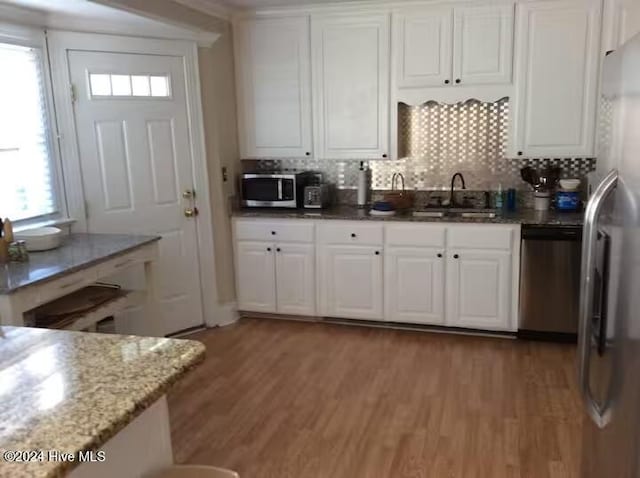 kitchen featuring appliances with stainless steel finishes, tasteful backsplash, sink, light hardwood / wood-style flooring, and white cabinets