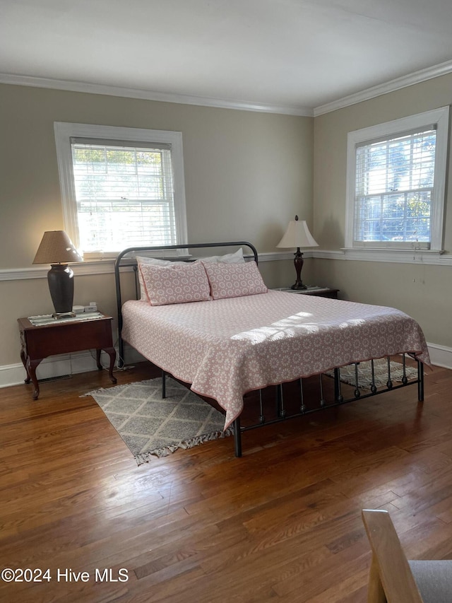 bedroom featuring wood-type flooring, multiple windows, and ornamental molding