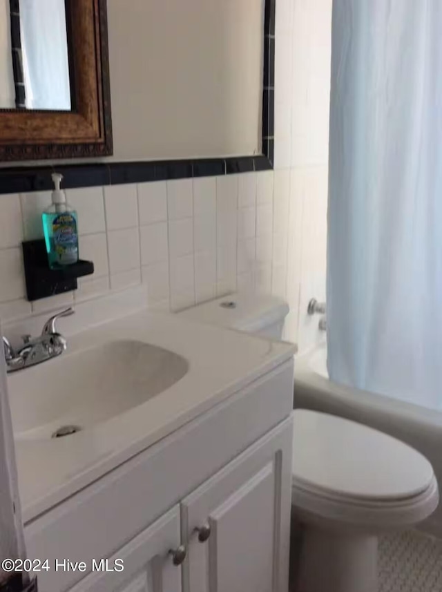 full bathroom featuring toilet, vanity, shower / tub combo with curtain, and tile walls