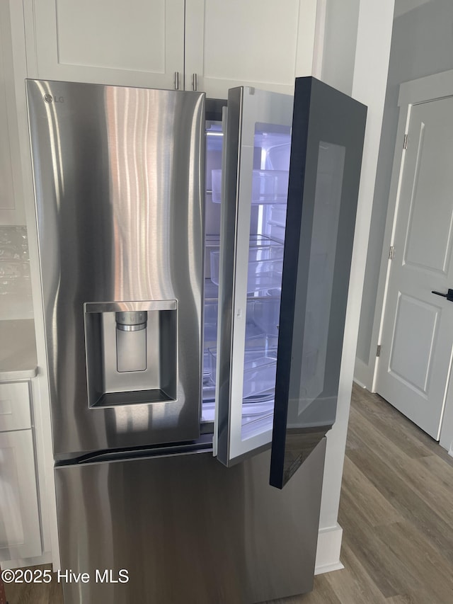 details with wood-type flooring, white cabinets, and stainless steel refrigerator with ice dispenser