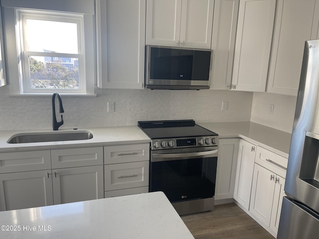 kitchen featuring dark wood-type flooring, sink, tasteful backsplash, appliances with stainless steel finishes, and white cabinets