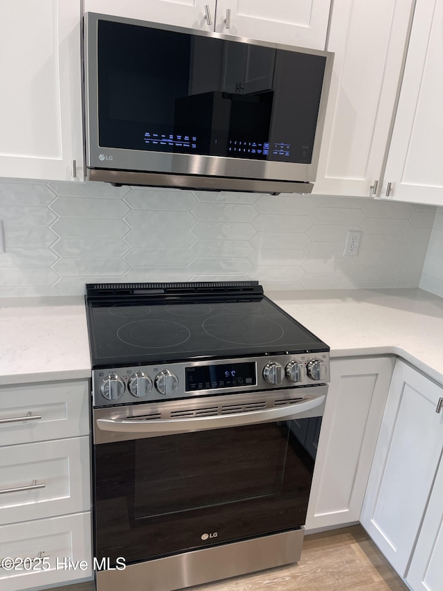 kitchen with white cabinetry, appliances with stainless steel finishes, decorative backsplash, and light hardwood / wood-style flooring