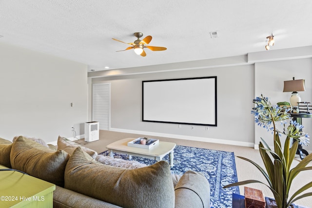 carpeted home theater room featuring ceiling fan and a textured ceiling