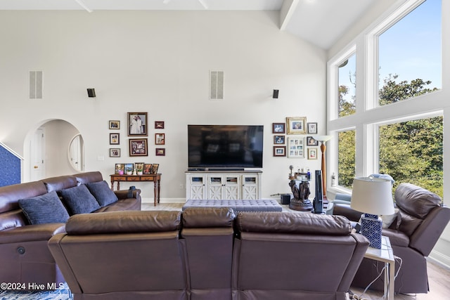 living room with beamed ceiling, light hardwood / wood-style flooring, and high vaulted ceiling