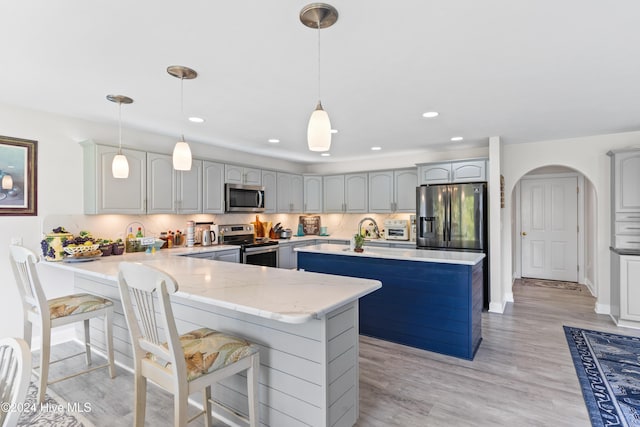 kitchen with pendant lighting, kitchen peninsula, appliances with stainless steel finishes, and light hardwood / wood-style flooring