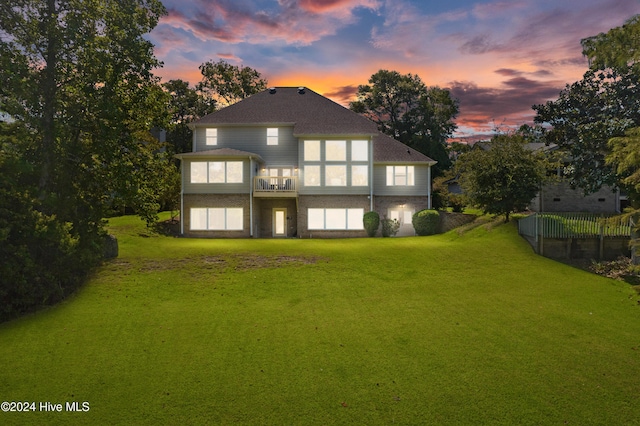 back house at dusk featuring a lawn