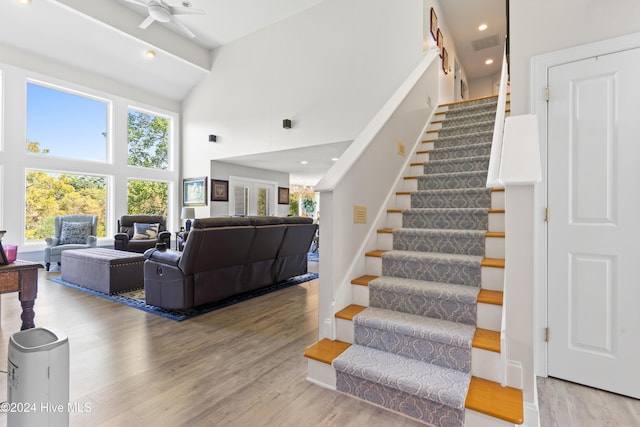 stairway featuring ceiling fan, hardwood / wood-style floors, and high vaulted ceiling