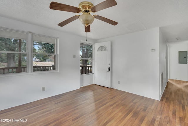 spare room with electric panel, ceiling fan, dark wood-type flooring, and a textured ceiling