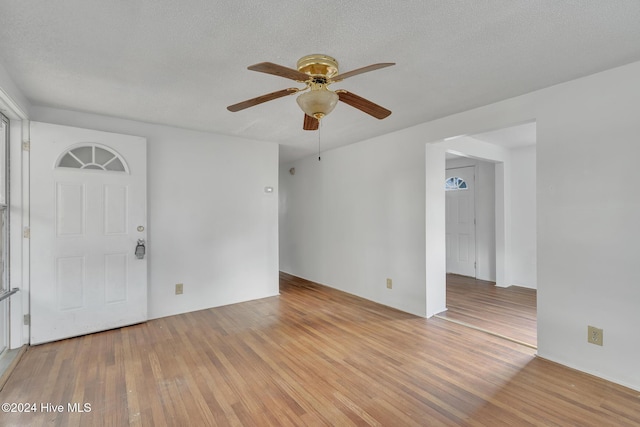 unfurnished room with ceiling fan, light wood-type flooring, and a textured ceiling