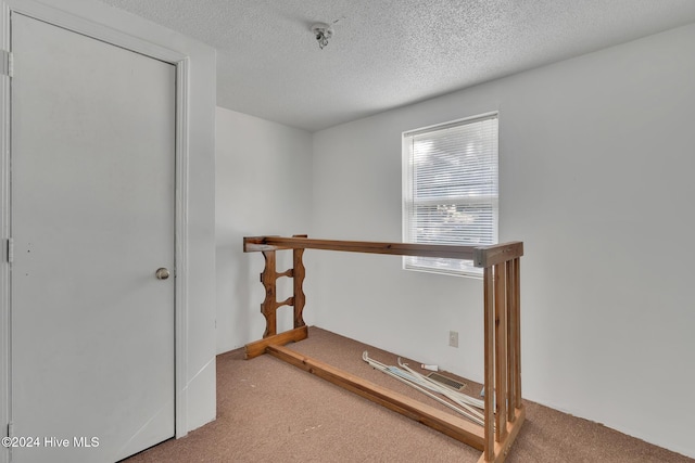 hall featuring carpet floors and a textured ceiling