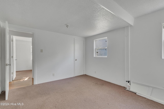 carpeted spare room with a textured ceiling