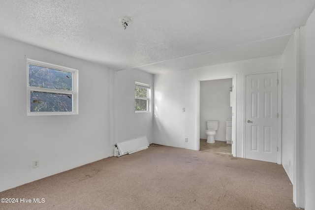 unfurnished room with carpet, radiator heating unit, and a textured ceiling