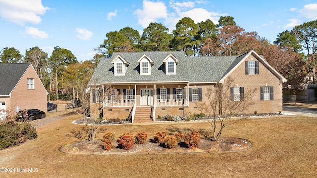 cape cod home with a front yard and a porch