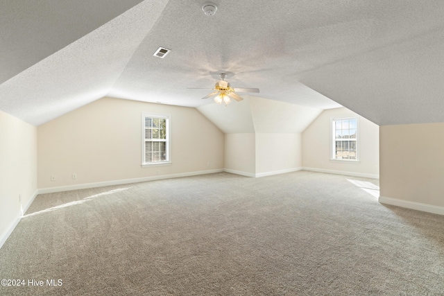 additional living space featuring ceiling fan, plenty of natural light, light carpet, and vaulted ceiling