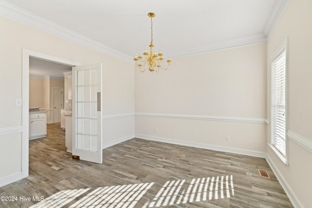 empty room featuring crown molding, hardwood / wood-style floors, and an inviting chandelier