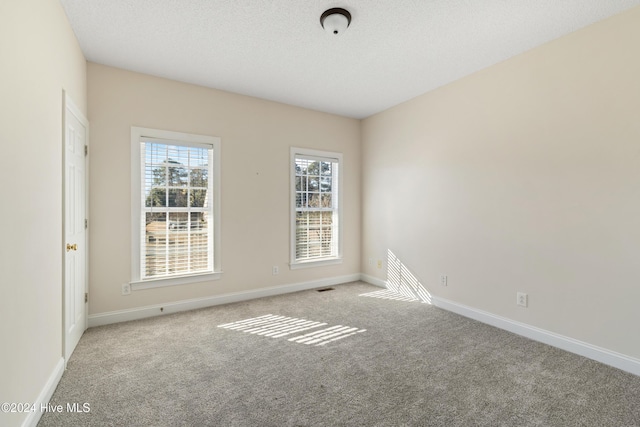 carpeted empty room with a textured ceiling