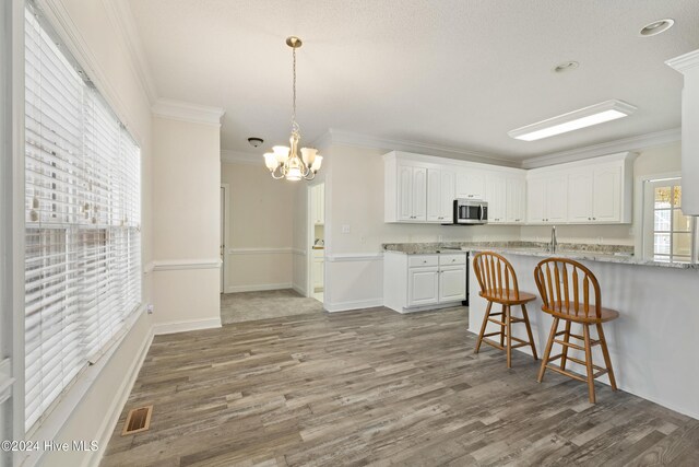 kitchen featuring a chandelier, wood-type flooring, white cabinetry, and crown molding