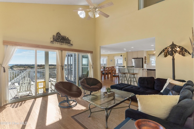 living room featuring ceiling fan, a high ceiling, and light hardwood / wood-style flooring