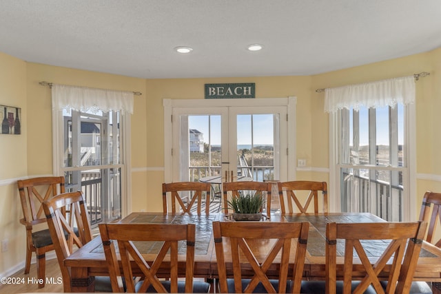 dining space featuring hardwood / wood-style floors, plenty of natural light, a textured ceiling, and french doors