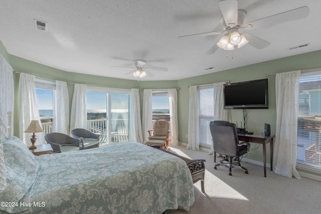 carpeted bedroom featuring multiple windows, ceiling fan, and a textured ceiling