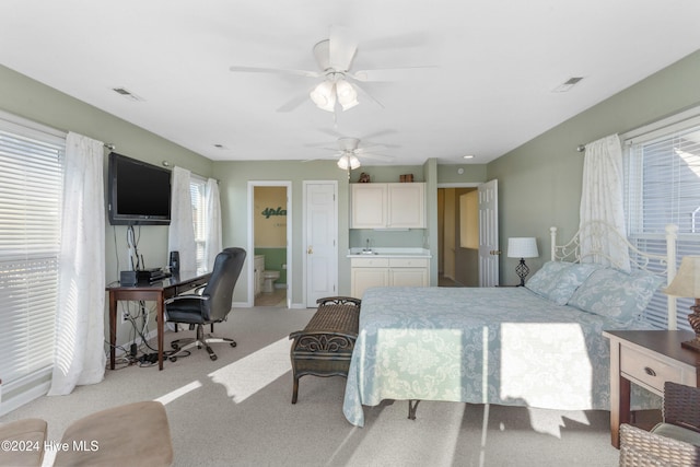 bedroom with ensuite bath, ceiling fan, and light colored carpet