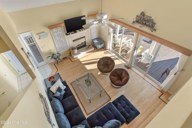 living room featuring a fireplace, a towering ceiling, hardwood / wood-style flooring, and ceiling fan