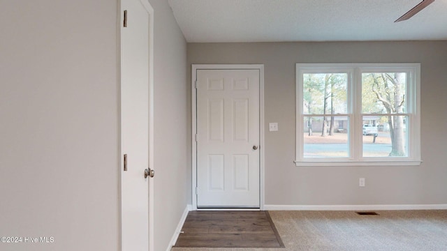 doorway to outside with ceiling fan and dark carpet