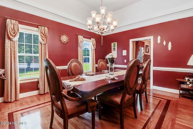 dining area featuring hardwood / wood-style floors, ornamental molding, a wealth of natural light, and a notable chandelier