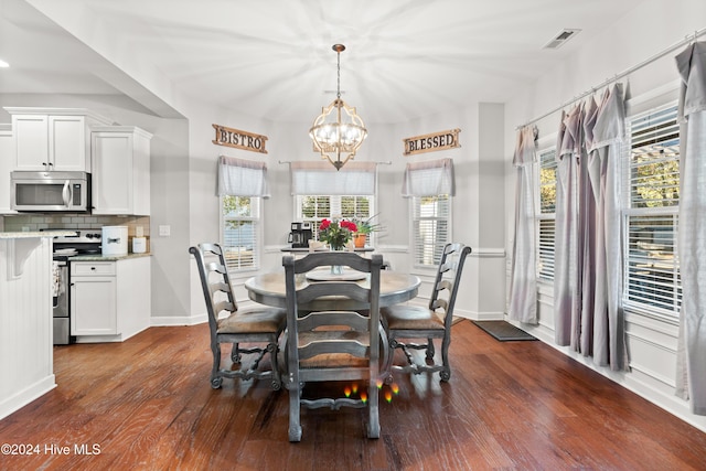 dining space featuring dark wood-type flooring, a wealth of natural light, and an inviting chandelier