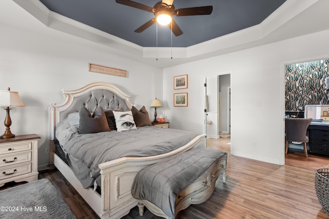 bedroom with ceiling fan, wood-type flooring, ornamental molding, and a raised ceiling