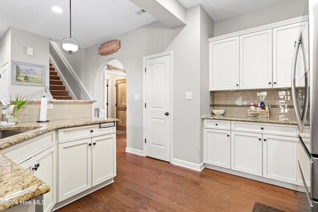 kitchen with pendant lighting, decorative backsplash, stainless steel refrigerator, white cabinetry, and light stone countertops