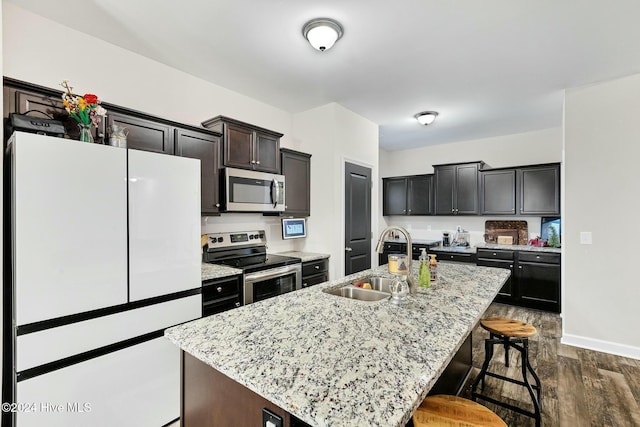 kitchen with sink, dark hardwood / wood-style flooring, a kitchen island with sink, and appliances with stainless steel finishes