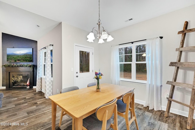 dining room with a notable chandelier, dark hardwood / wood-style floors, and vaulted ceiling