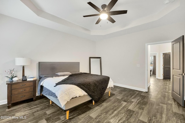 bedroom featuring dark hardwood / wood-style floors, ceiling fan, and a raised ceiling