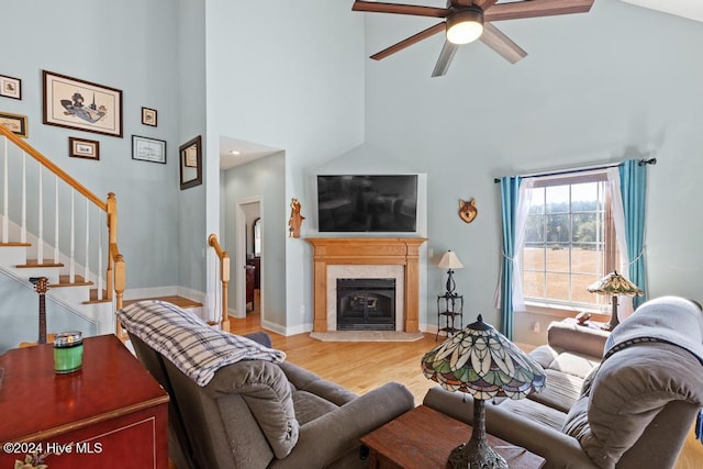 living room with a tile fireplace, ceiling fan, hardwood / wood-style floors, and high vaulted ceiling