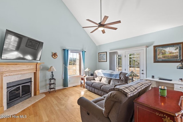 living room with a high end fireplace, a wealth of natural light, light hardwood / wood-style floors, and high vaulted ceiling