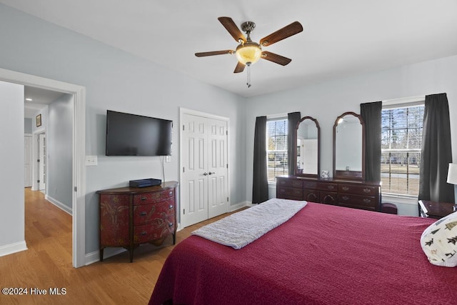 bedroom with ceiling fan, light hardwood / wood-style floors, and a closet