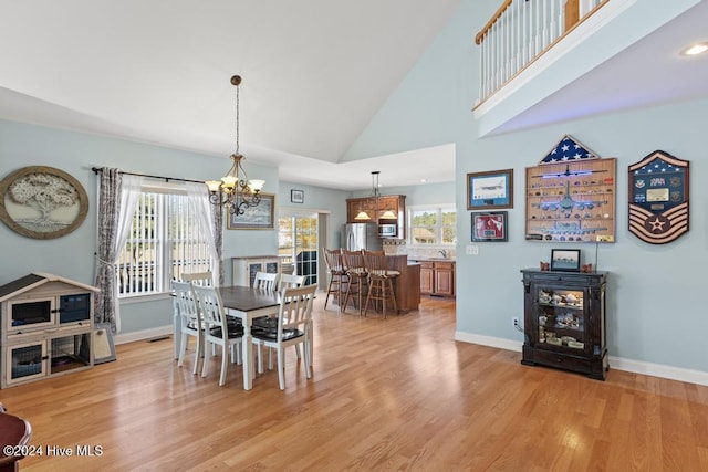 dining area featuring a chandelier, light wood-type flooring, high vaulted ceiling, and a healthy amount of sunlight