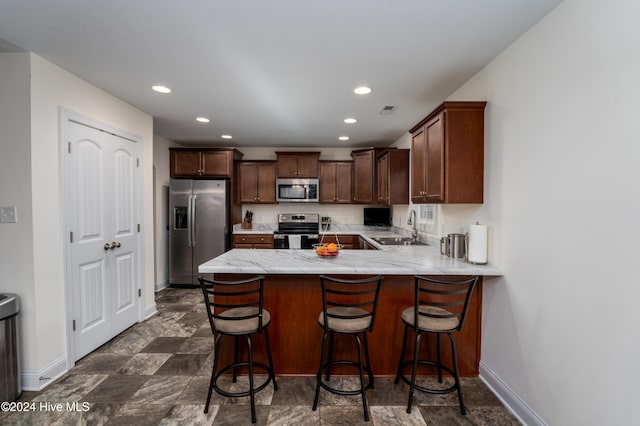 kitchen with kitchen peninsula, a kitchen bar, stainless steel appliances, and sink