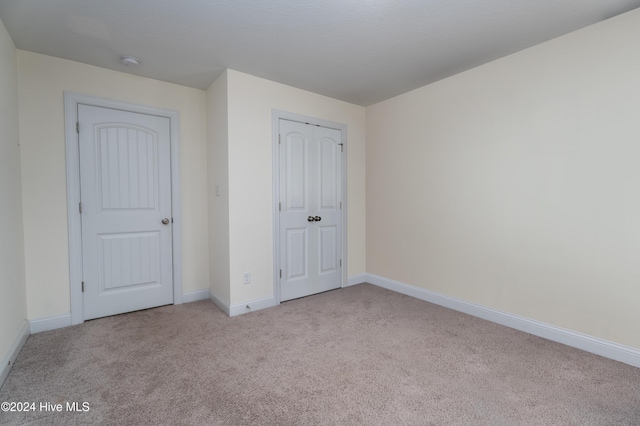 unfurnished bedroom with light carpet and a closet