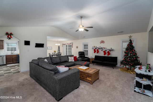 living room with ceiling fan with notable chandelier, light colored carpet, vaulted ceiling, and sink