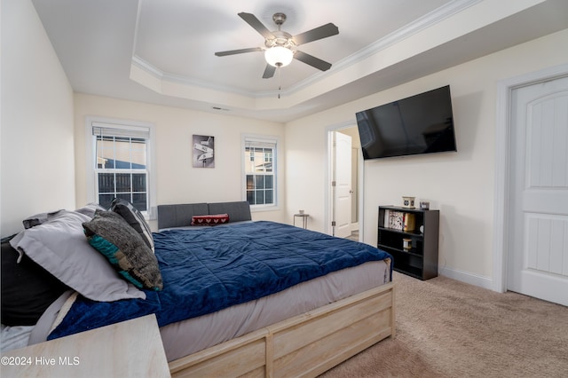 carpeted bedroom with a tray ceiling, ceiling fan, and ornamental molding