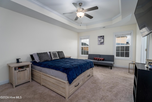 bedroom featuring a tray ceiling, multiple windows, crown molding, and ceiling fan