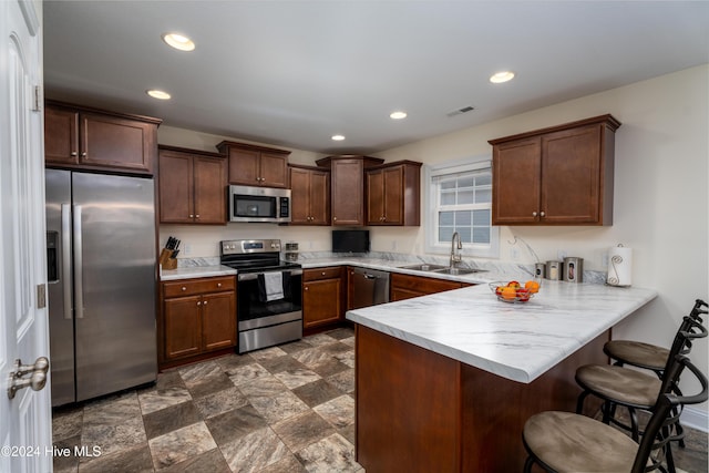 kitchen with a kitchen bar, kitchen peninsula, sink, and appliances with stainless steel finishes