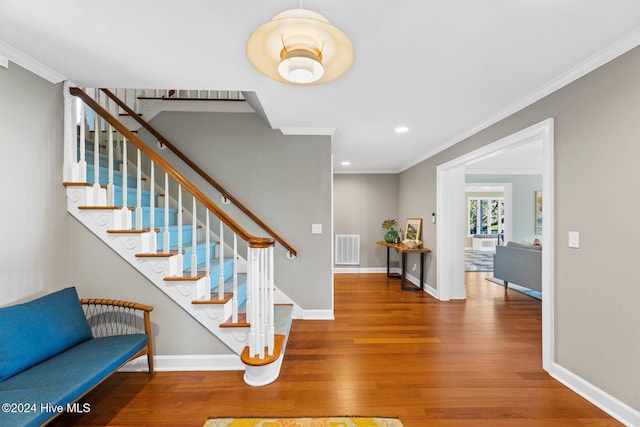 staircase featuring ornamental molding and hardwood / wood-style flooring