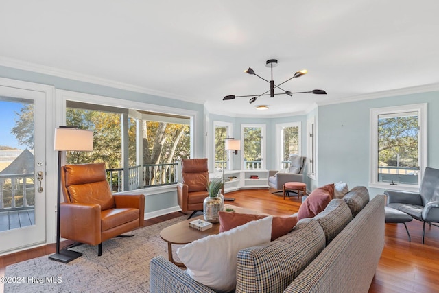 living room with hardwood / wood-style flooring, crown molding, plenty of natural light, and a notable chandelier