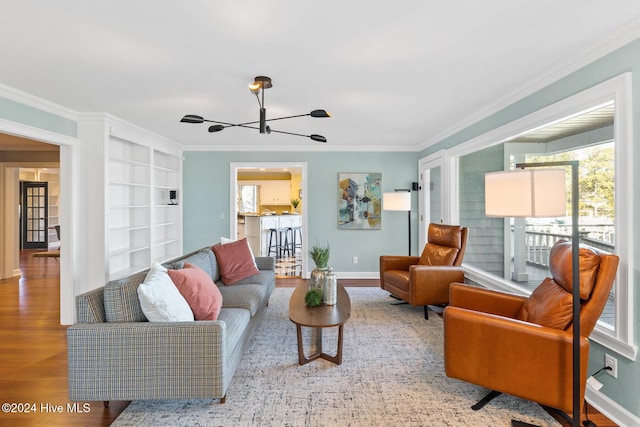 living room featuring hardwood / wood-style flooring, built in features, ornamental molding, and an inviting chandelier