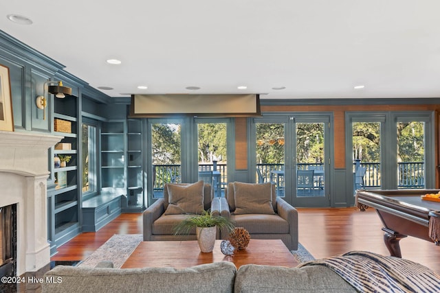 living room with built in shelves, billiards, ornamental molding, and hardwood / wood-style flooring