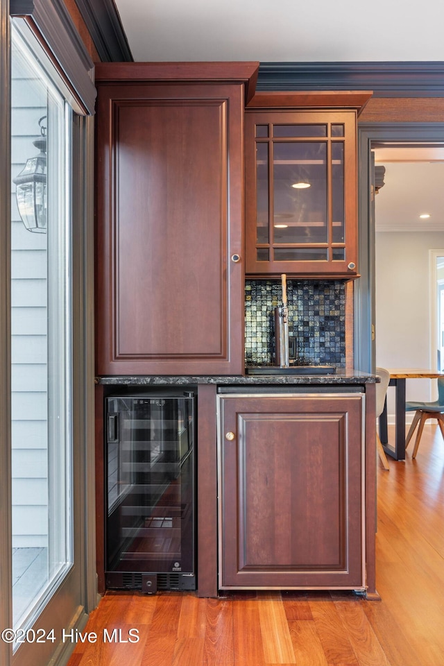 bar featuring decorative backsplash, light wood-type flooring, and beverage cooler