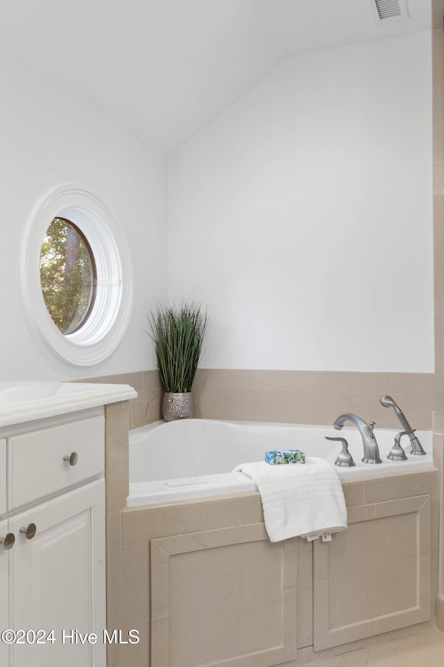 bathroom with a relaxing tiled tub and vaulted ceiling